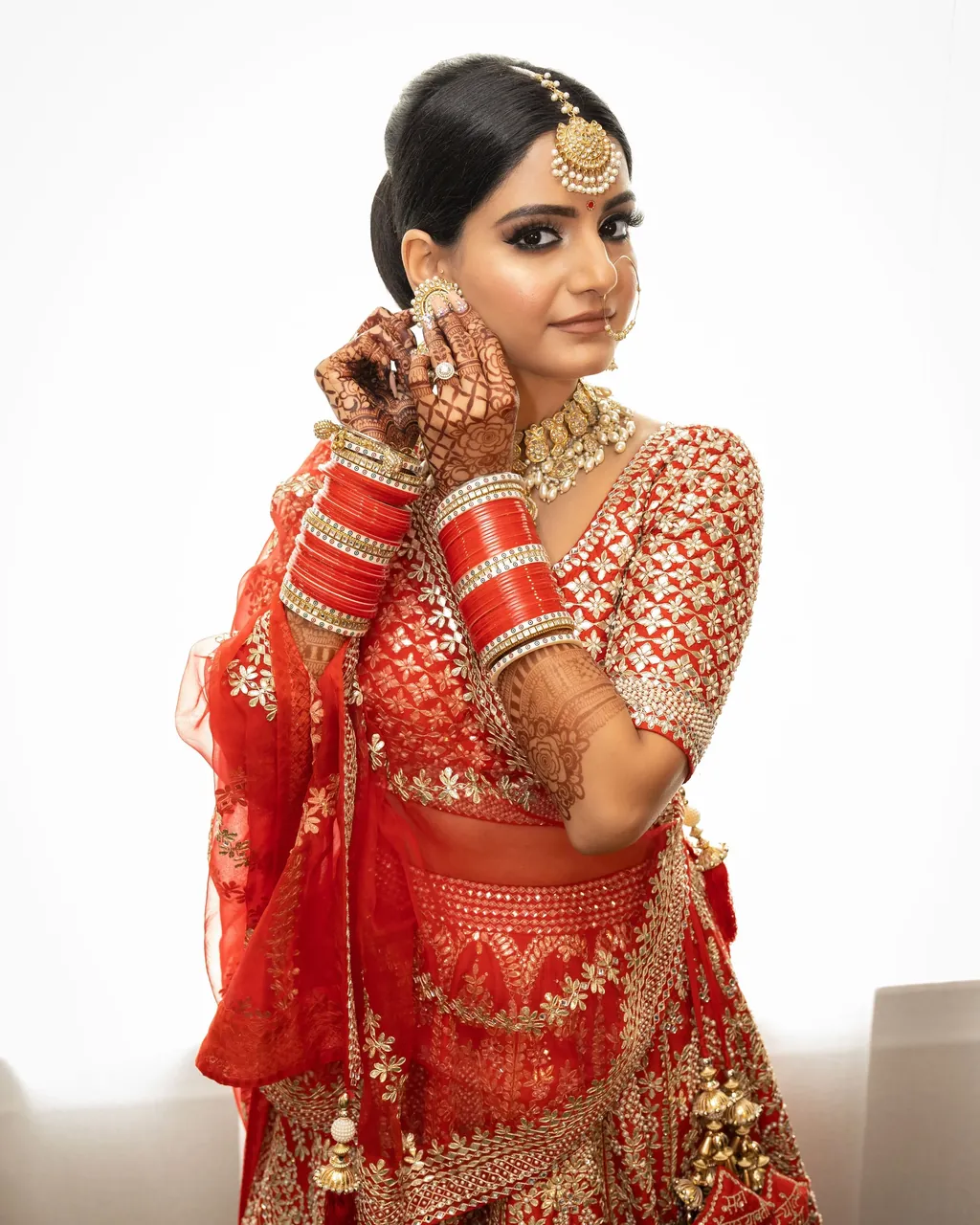 Punjabi bride in red with chooda bangles adjusting her dupatta