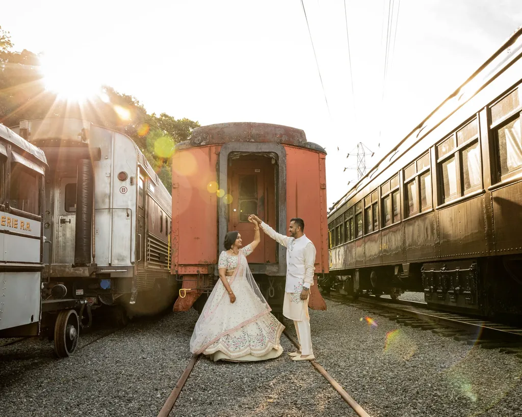 Couple dancing between vintage train cars at sunset