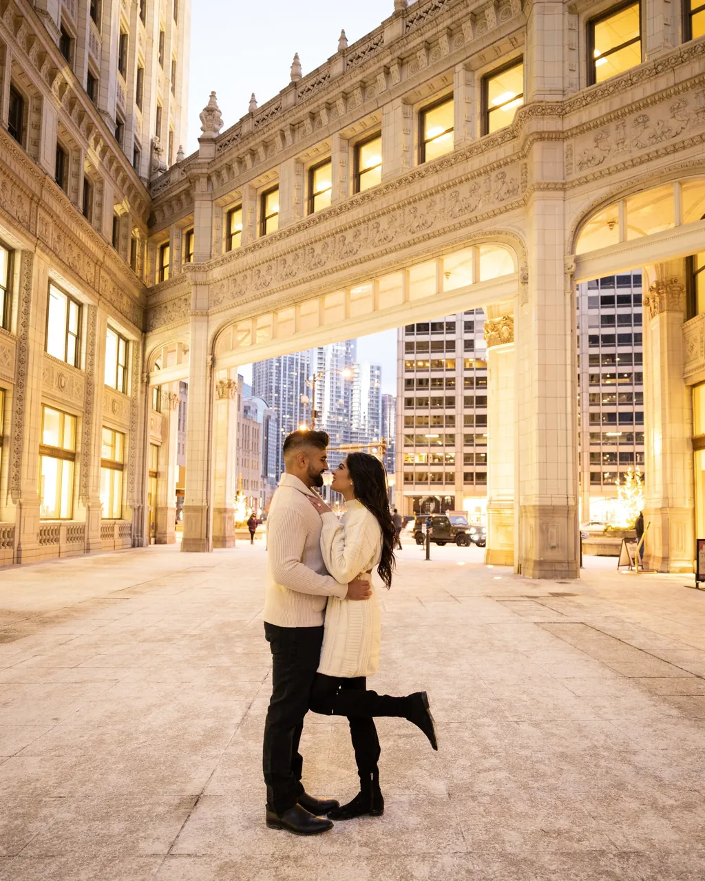 Couple kissing in a grand stone arcade at dusk