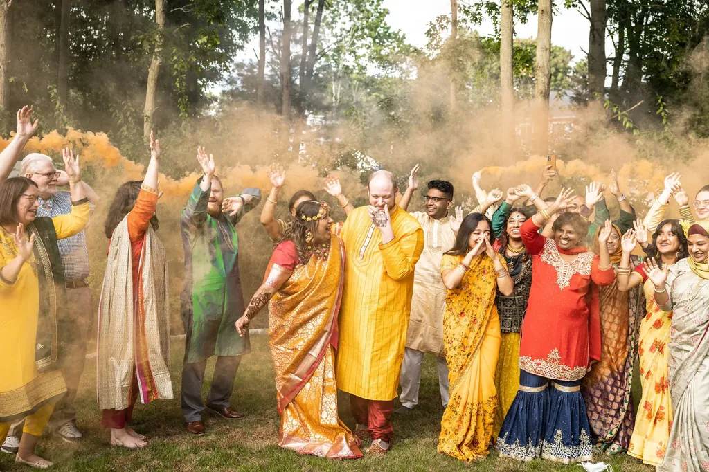 Family dancing in clouds of colour at a pre-wedding celebration