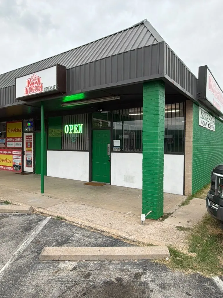 The Kush Kingdom Dispensary storefront with its green door and OPEN sign