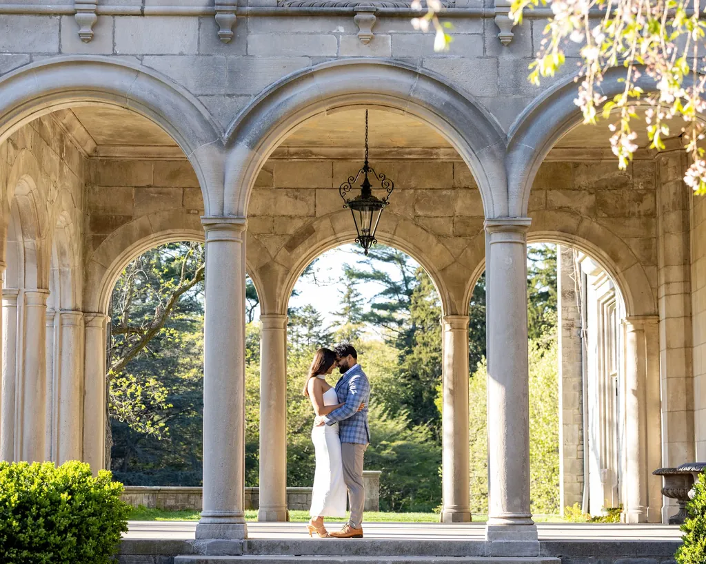 Couple embracing under a sunlit stone arcade with a hanging lantern