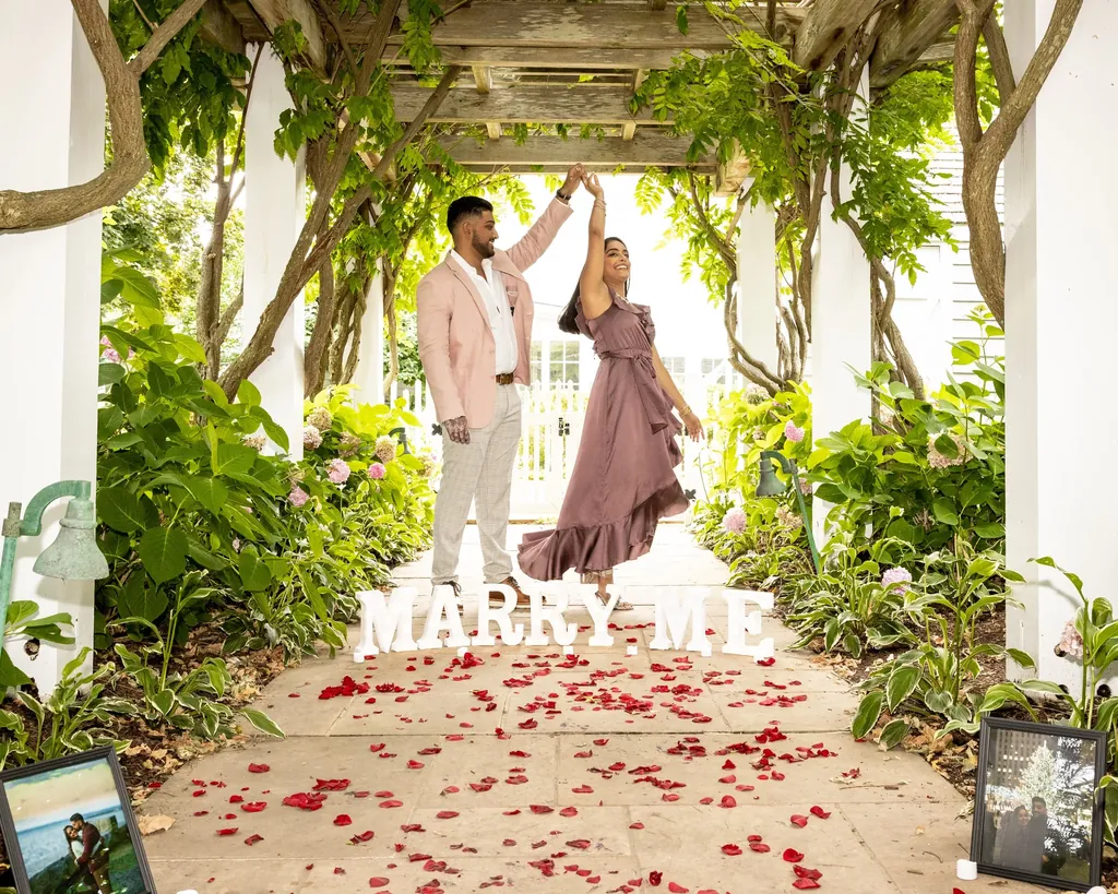 Couple celebrating after a proposal under a wisteria pergola