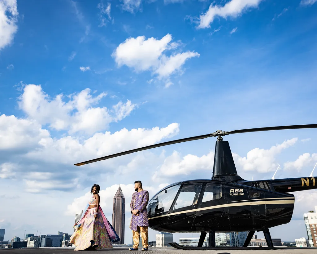 Bride and groom stepping out beside a helicopter on a city helipad