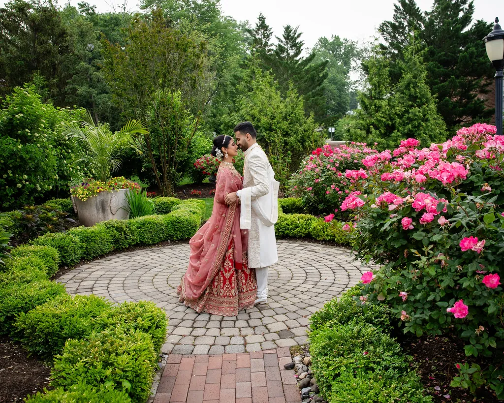 Couple touching foreheads on a stone patio in a rose garden