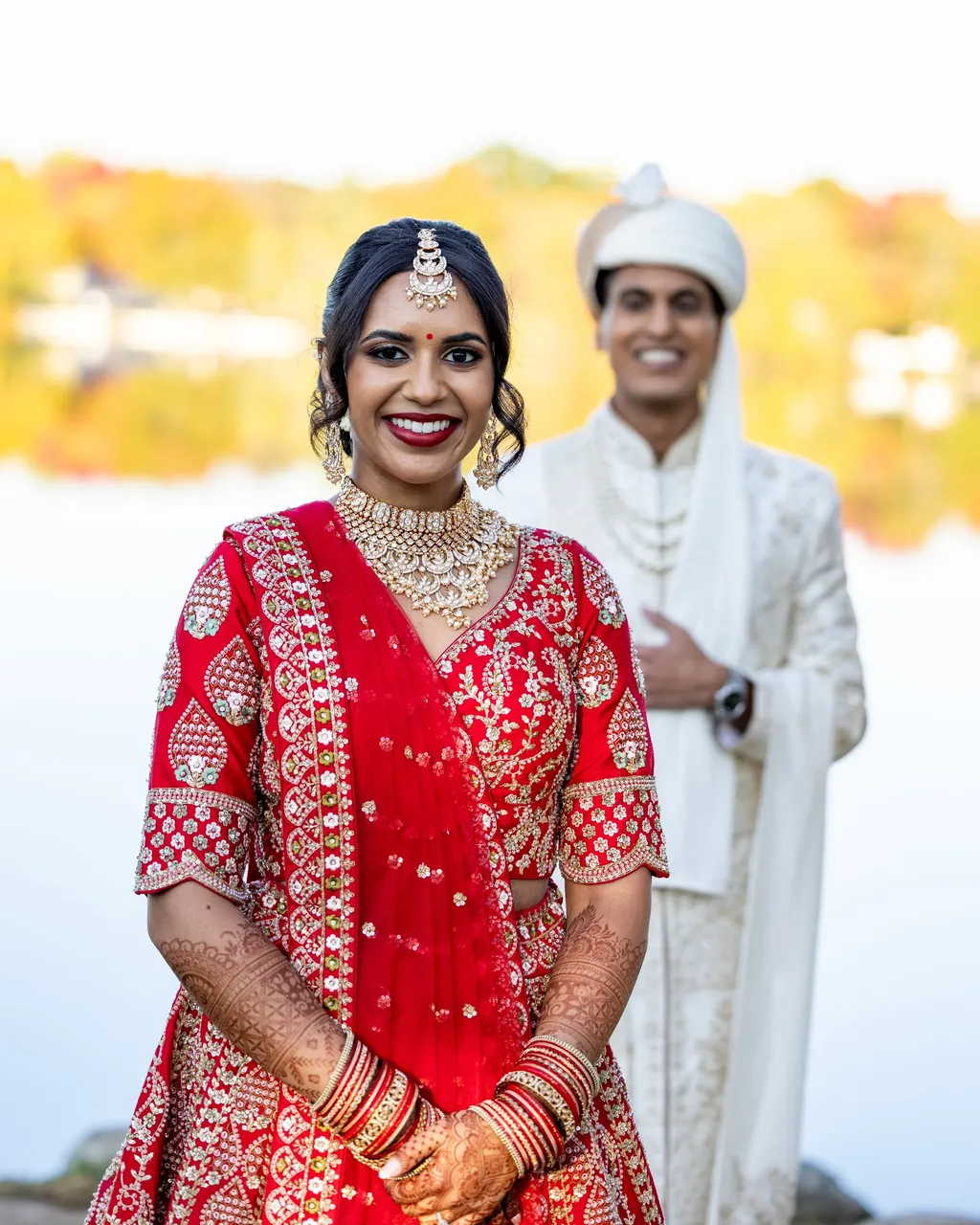 Smiling bride in a red saree with the groom in white