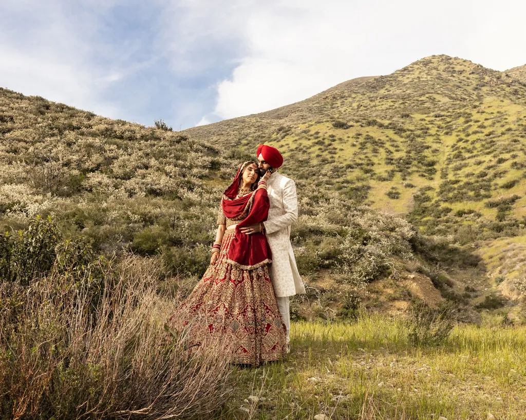 Sikh couple embracing on a hillside of dry grass