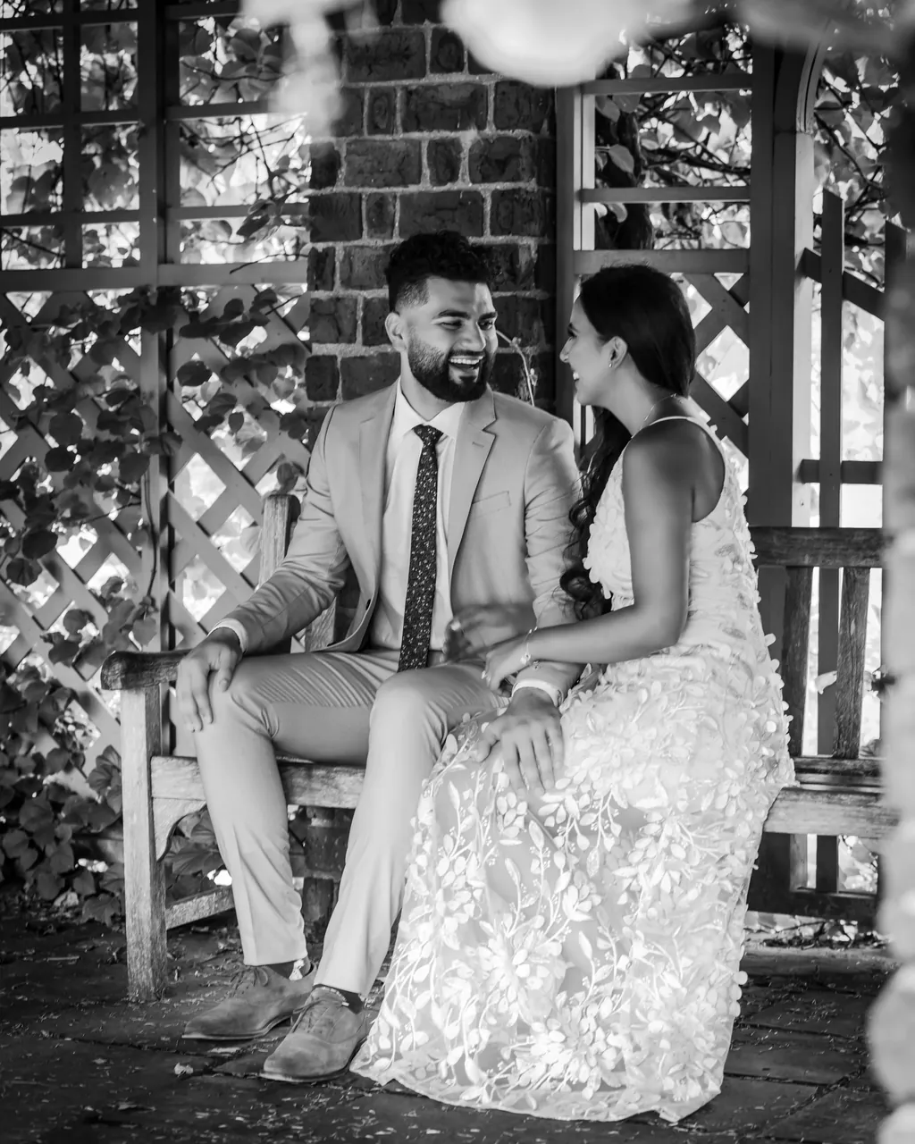 Black and white portrait of a couple seated under a garden lattice
