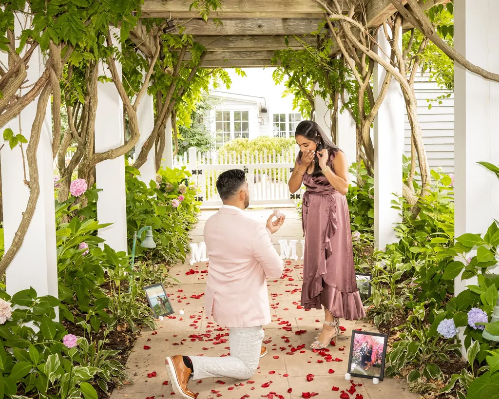 Surprise proposal under a wisteria pergola lined with rose petals