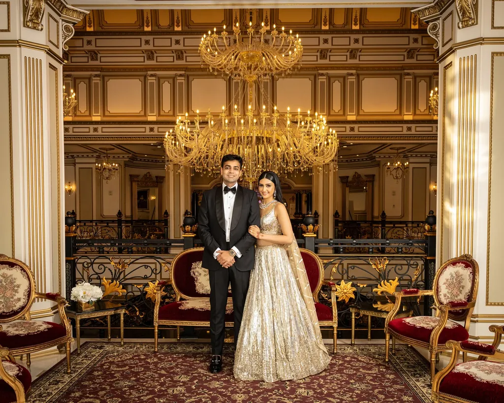 Bride and groom in a gilded ballroom under crystal chandeliers