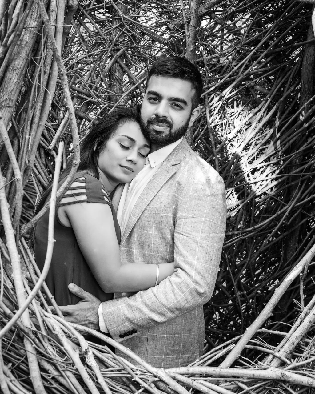 Black and white portrait of a couple embracing among branches
