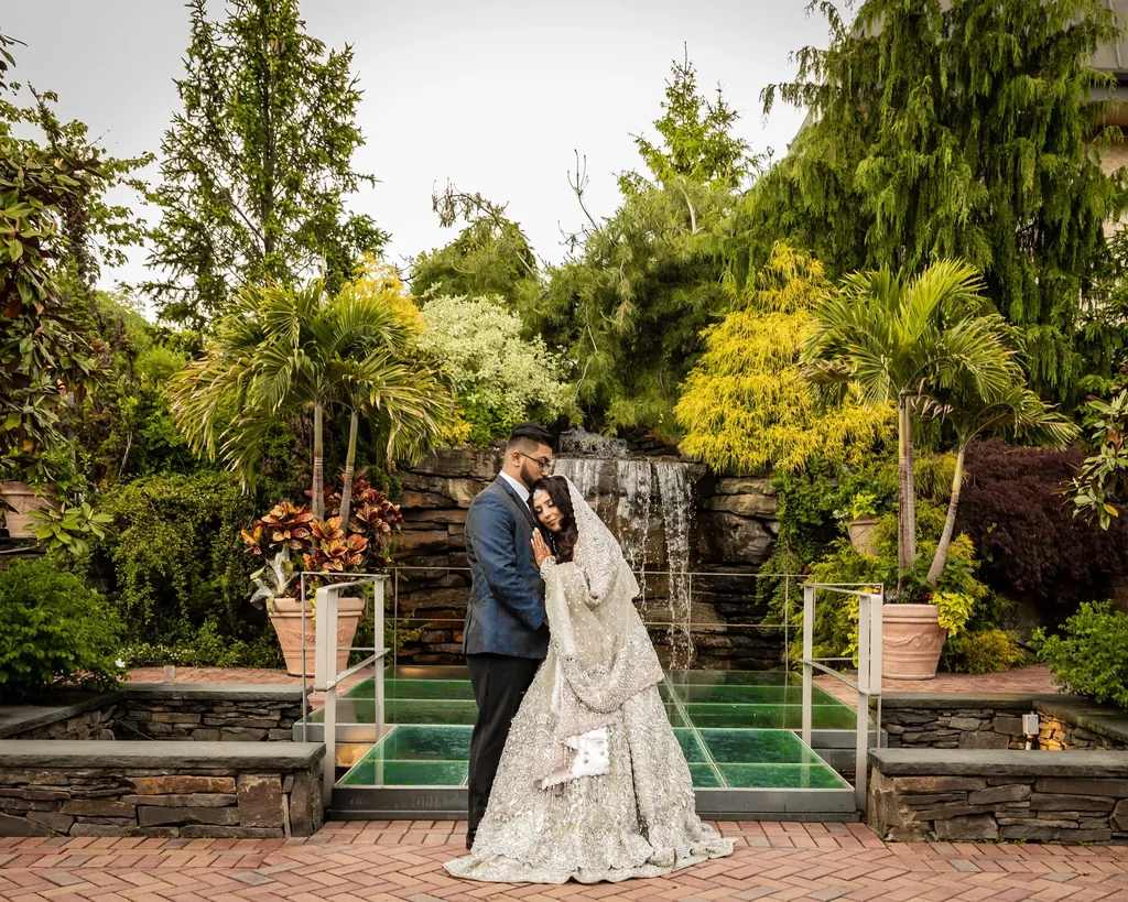 Couple in a garden beside a waterfall and footbridge