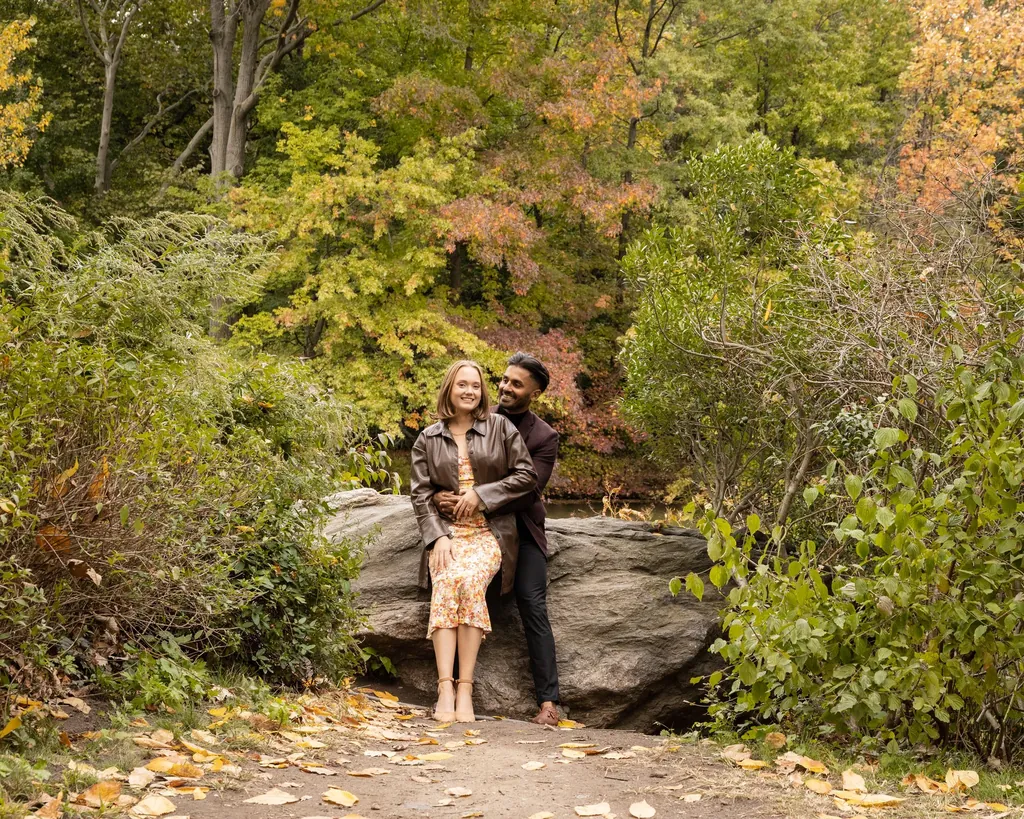 Couple standing among autumn trees and rocks
