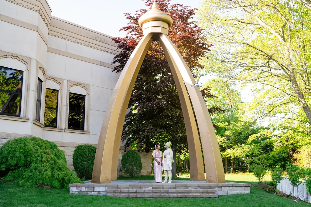 Couple beneath a tall golden arch on a venue lawn