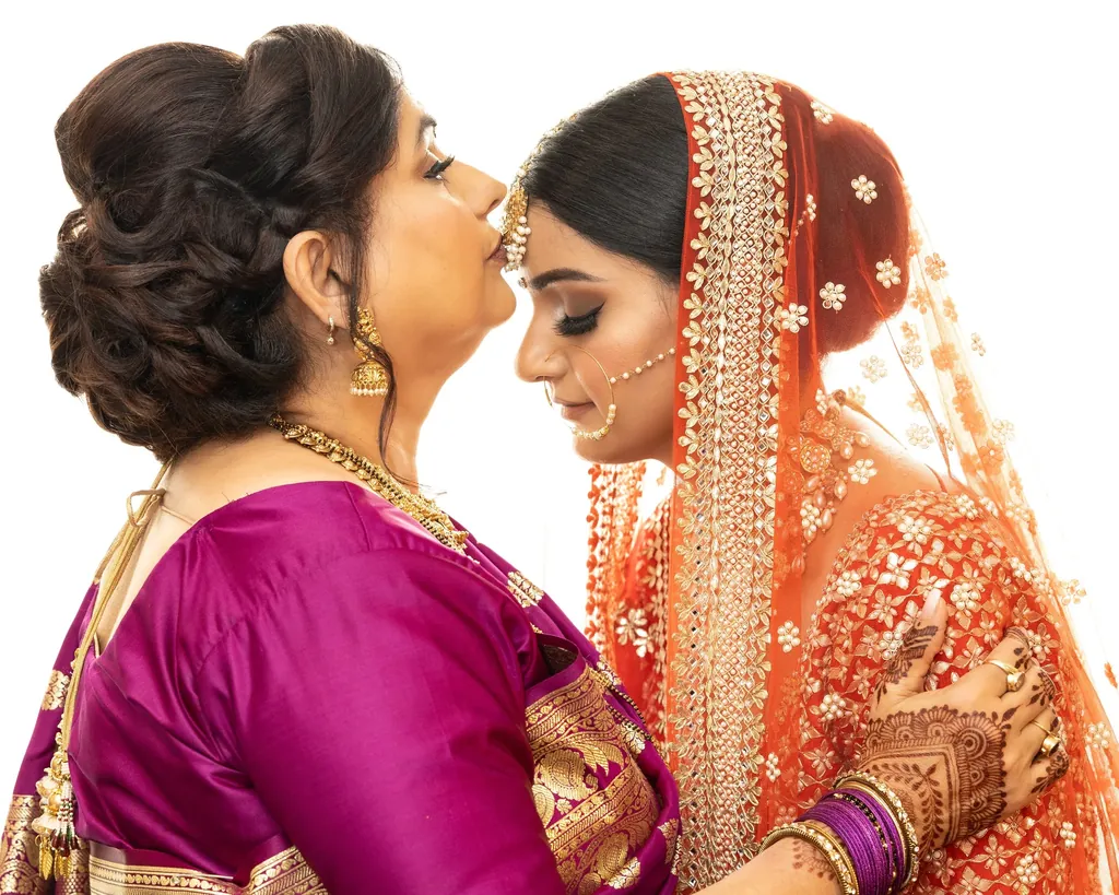 Mother kissing the bride on the forehead before the ceremony
