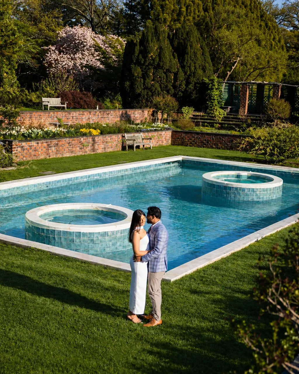 Couple embracing beside an estate pool and garden