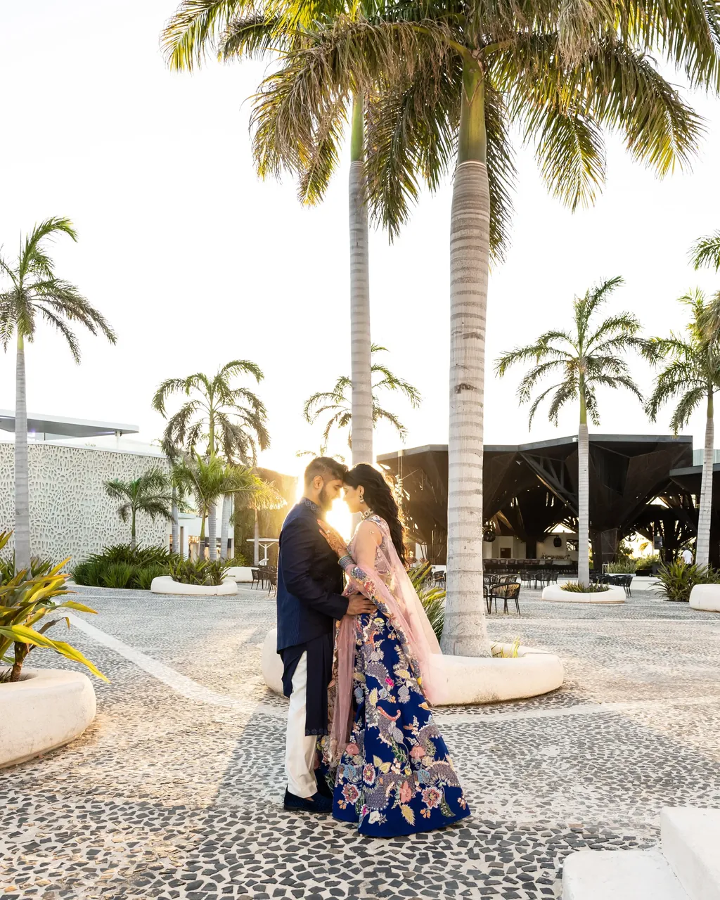 Bride and groom under palm trees at golden hour