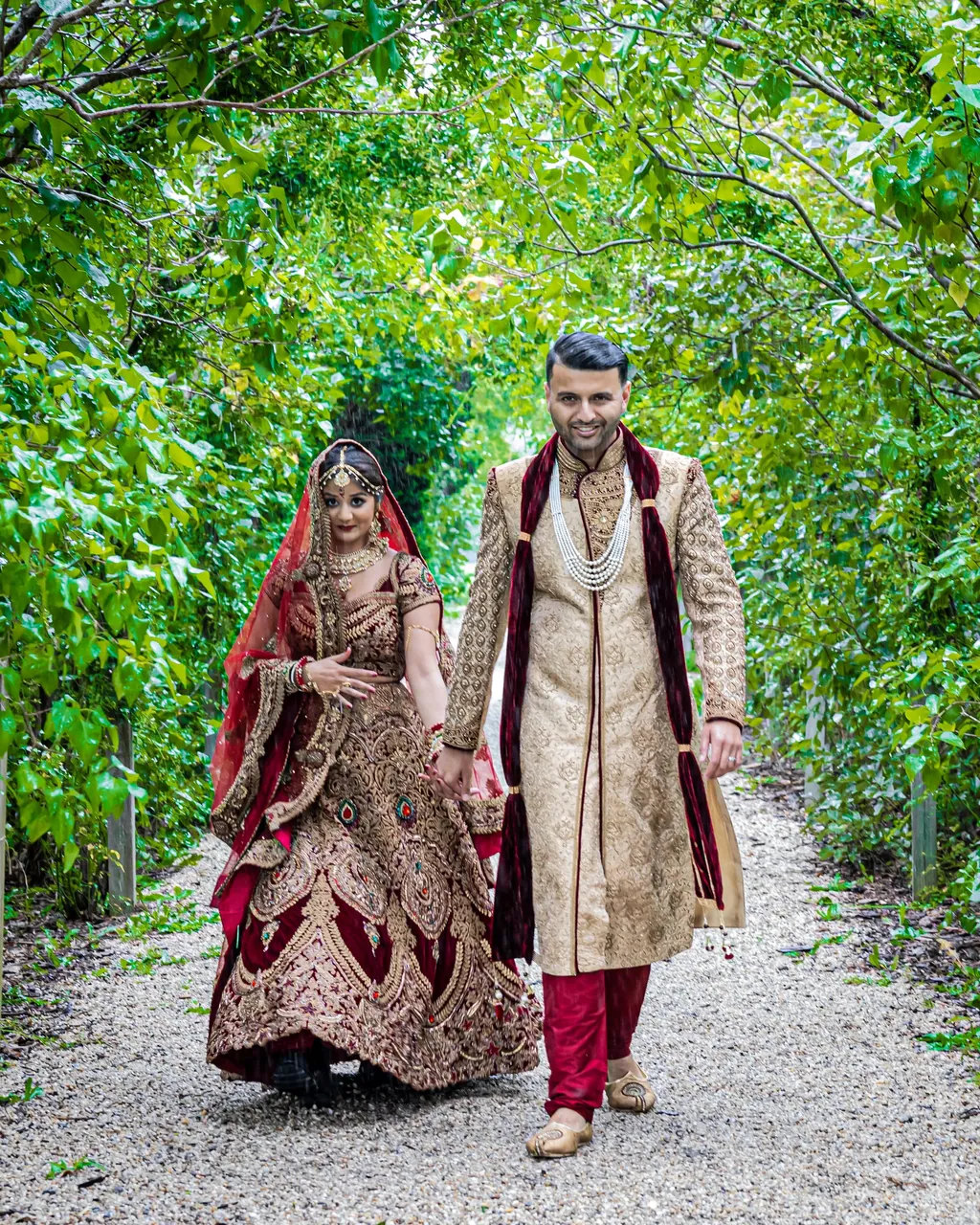 Bride and groom walking a garden path in red and gold