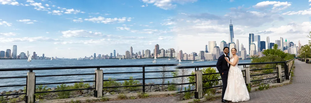 Bride and groom on the waterfront promenade with the lower Manhattan skyline behind them