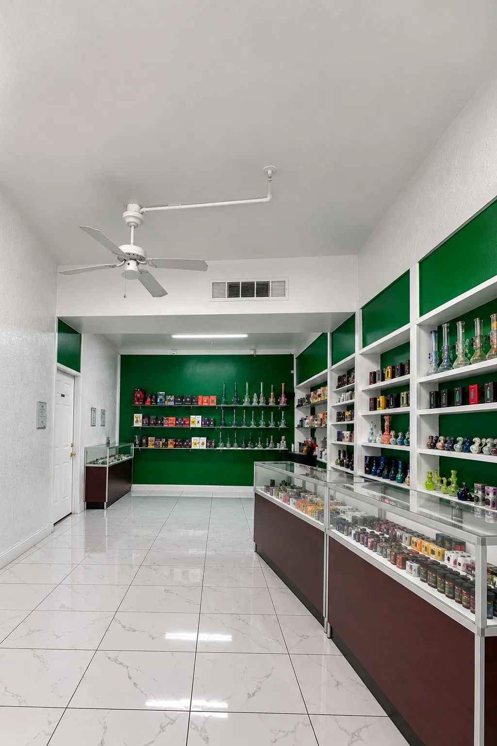The bright interior of Kush Kingdom with white walls, green shelving and glass cases