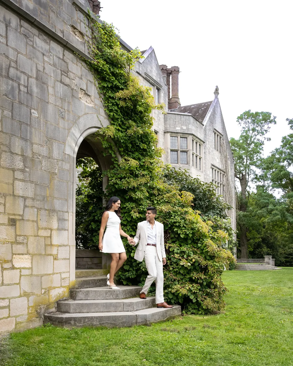 Couple walking up steps beside a stone manor