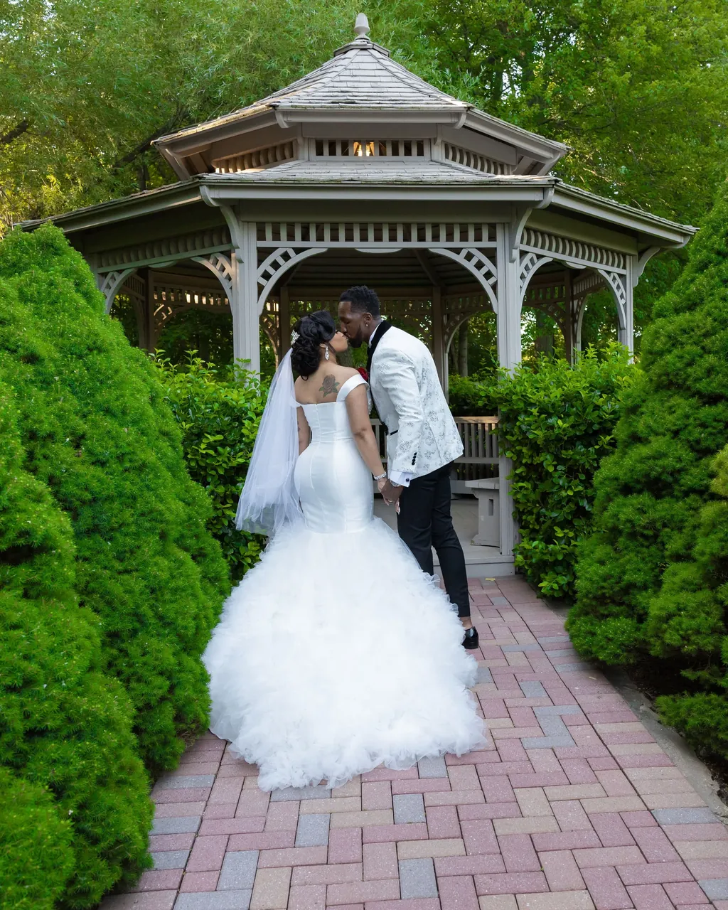 Bride and groom kissing in front of a white gazebo