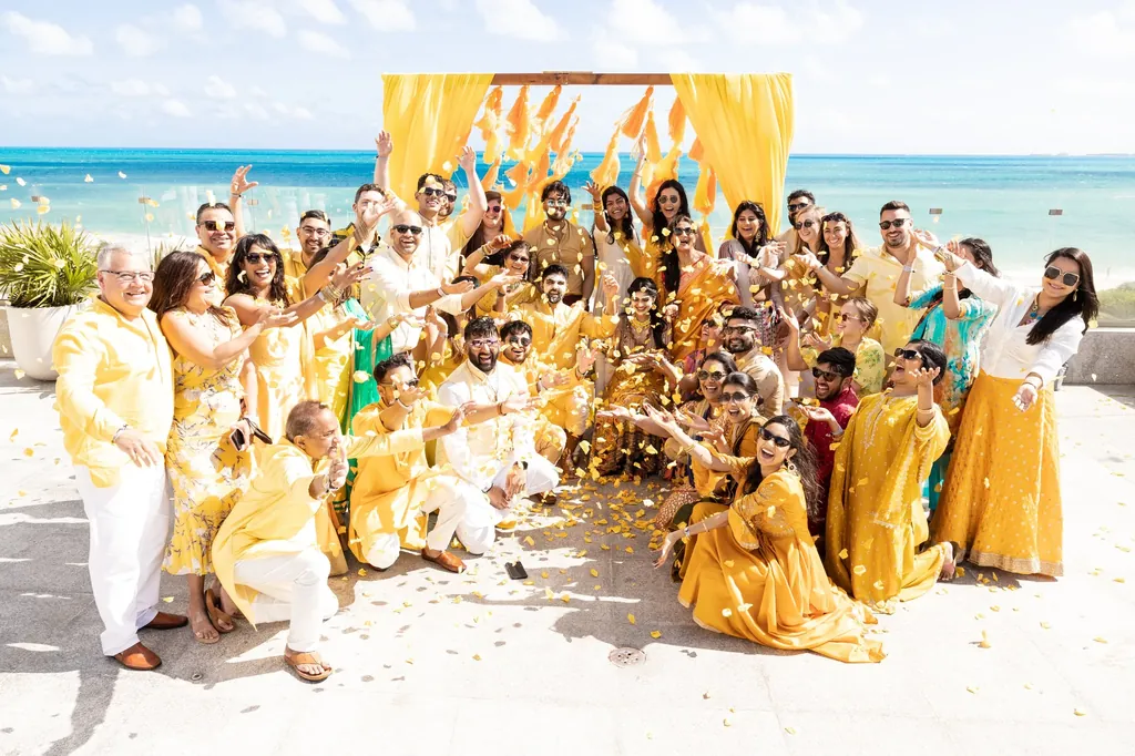 Haldi celebration on the beach, family in yellow throwing petals