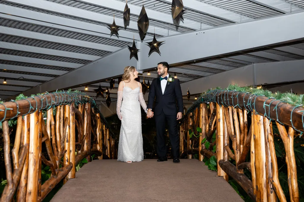 Bride and groom on a rustic wooden bridge under hanging lanterns