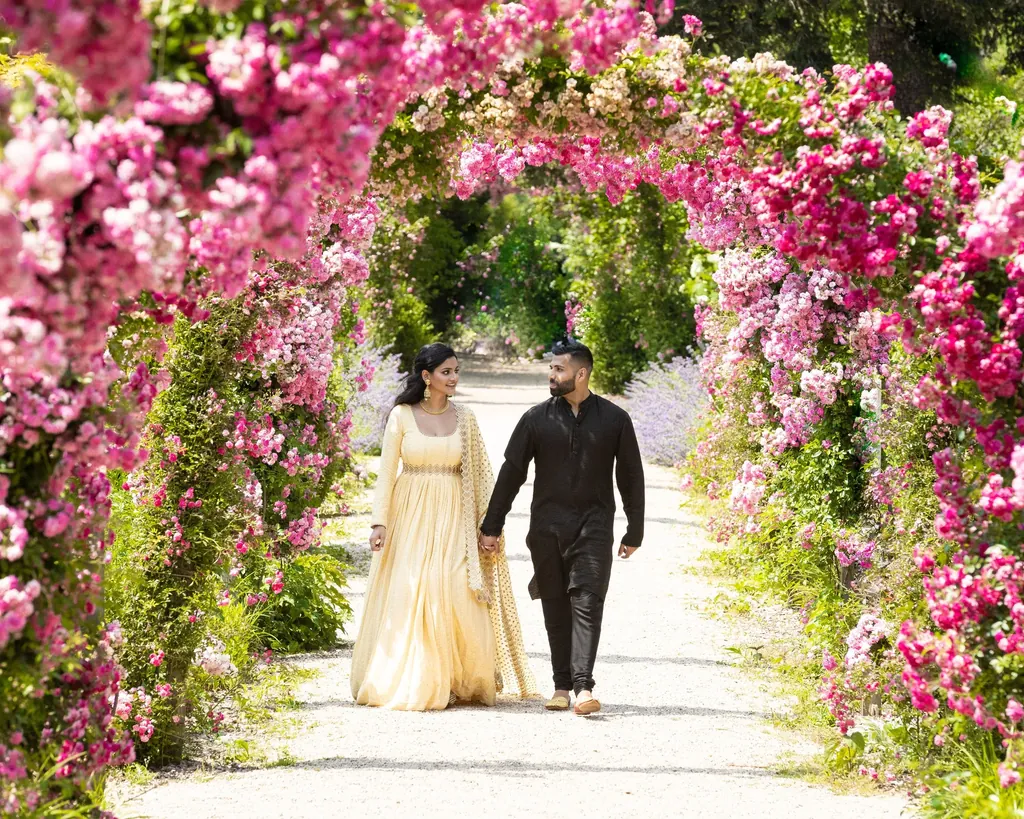 Couple walking under an arch of pink bougainvillea